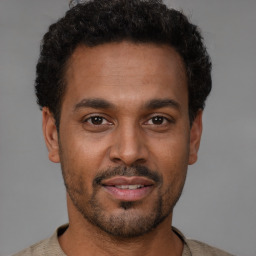 Joyful latino young-adult male with short  brown hair and brown eyes