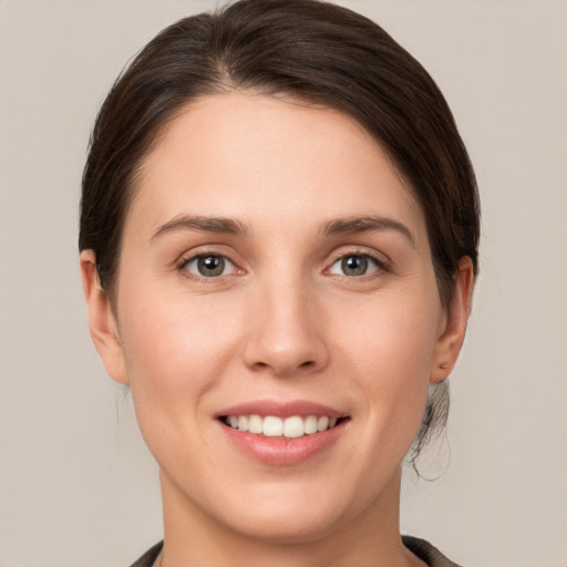 Joyful white young-adult female with medium  brown hair and grey eyes