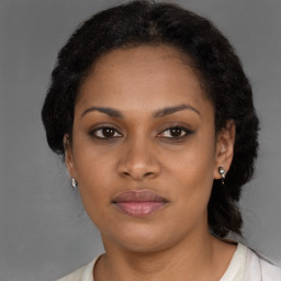 Joyful black young-adult female with long  brown hair and brown eyes
