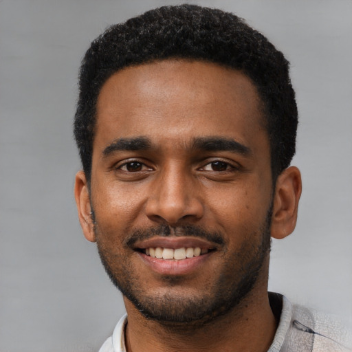 Joyful black young-adult male with short  black hair and brown eyes