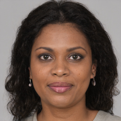 Joyful black young-adult female with long  brown hair and brown eyes