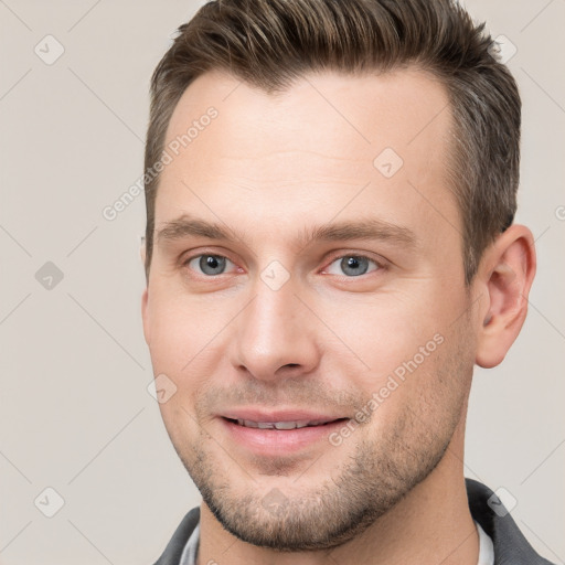 Joyful white young-adult male with short  brown hair and grey eyes