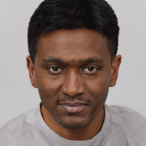 Joyful black young-adult male with short  black hair and brown eyes