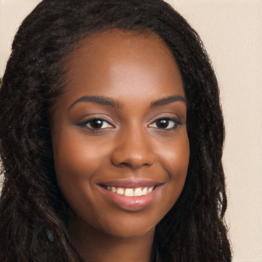 Joyful black young-adult female with long  brown hair and brown eyes