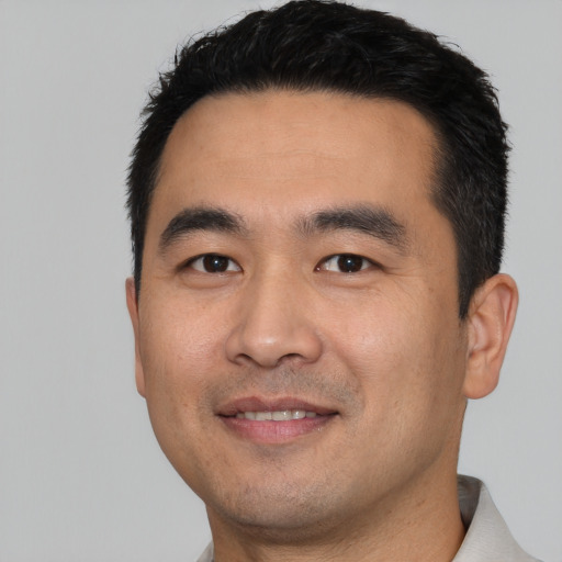 Joyful asian young-adult male with short  black hair and brown eyes