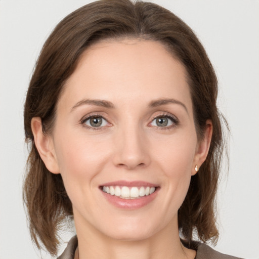 Joyful white young-adult female with medium  brown hair and grey eyes