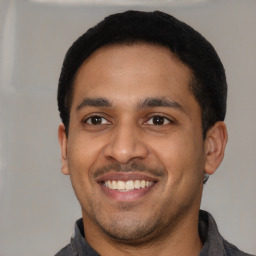 Joyful latino young-adult male with short  black hair and brown eyes