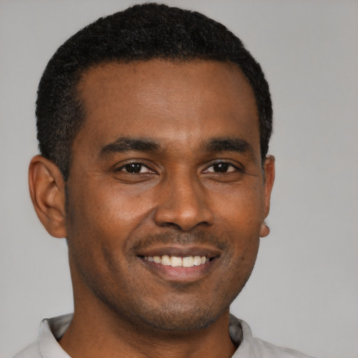 Joyful black young-adult male with short  black hair and brown eyes