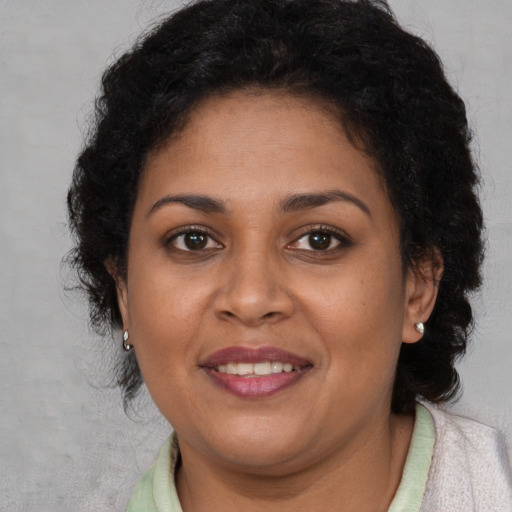 Joyful black adult female with medium  brown hair and brown eyes