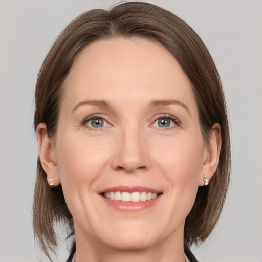 Joyful white adult female with medium  brown hair and grey eyes