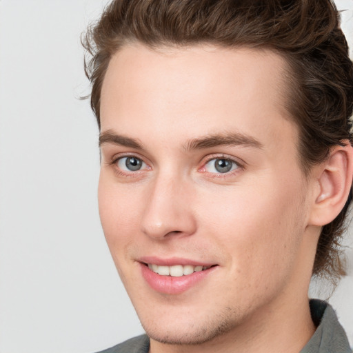 Joyful white young-adult male with medium  brown hair and grey eyes