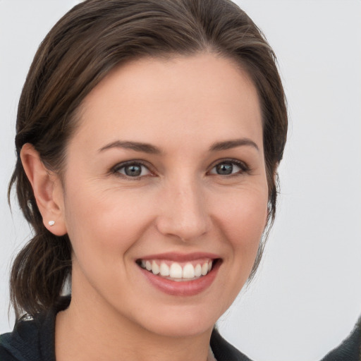 Joyful white young-adult female with medium  brown hair and grey eyes