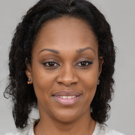 Joyful black young-adult female with long  brown hair and brown eyes