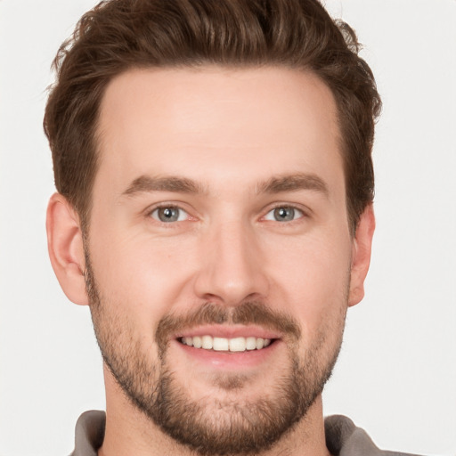 Joyful white young-adult male with short  brown hair and grey eyes