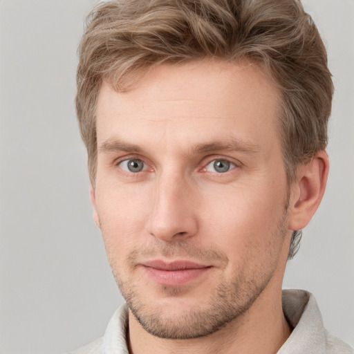 Joyful white young-adult male with short  brown hair and grey eyes