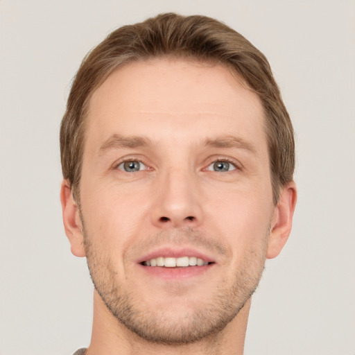 Joyful white young-adult male with short  brown hair and grey eyes