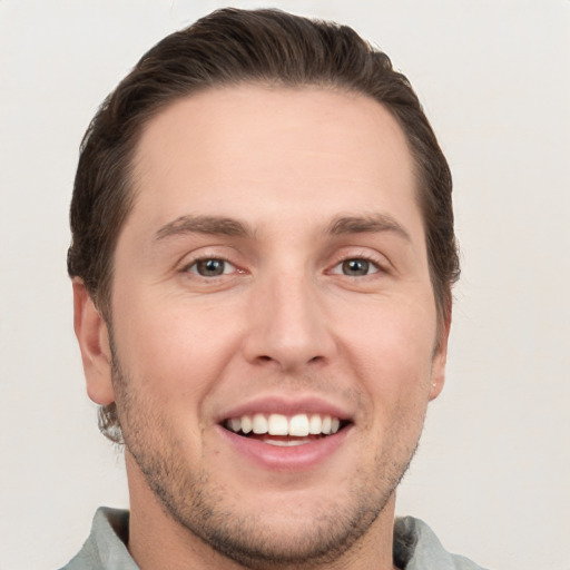 Joyful white young-adult male with short  brown hair and grey eyes