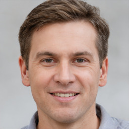 Joyful white young-adult male with short  brown hair and grey eyes