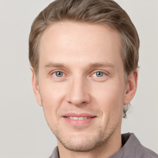 Joyful white young-adult male with short  brown hair and grey eyes