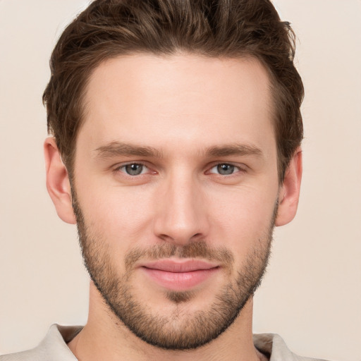 Joyful white young-adult male with short  brown hair and grey eyes