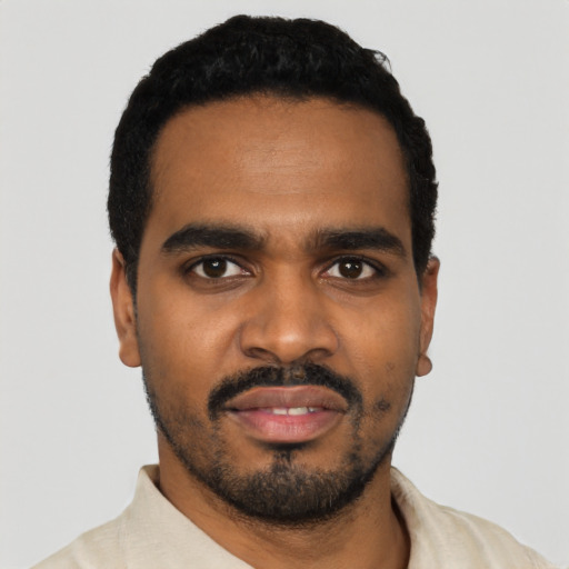 Joyful black young-adult male with short  black hair and brown eyes
