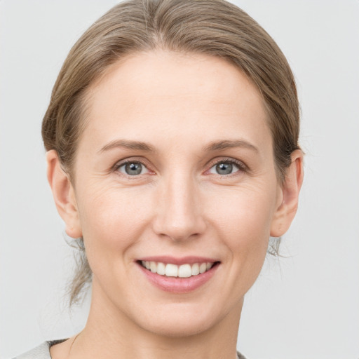 Joyful white young-adult female with medium  brown hair and grey eyes