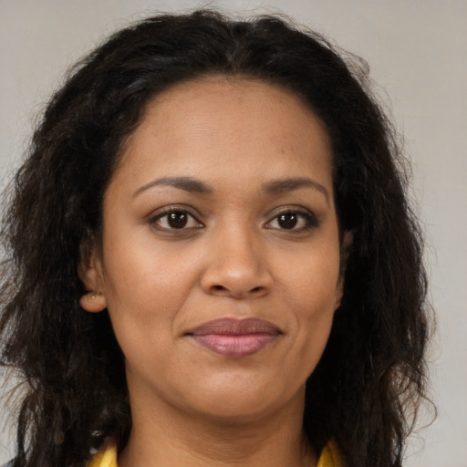 Joyful black young-adult female with long  brown hair and brown eyes