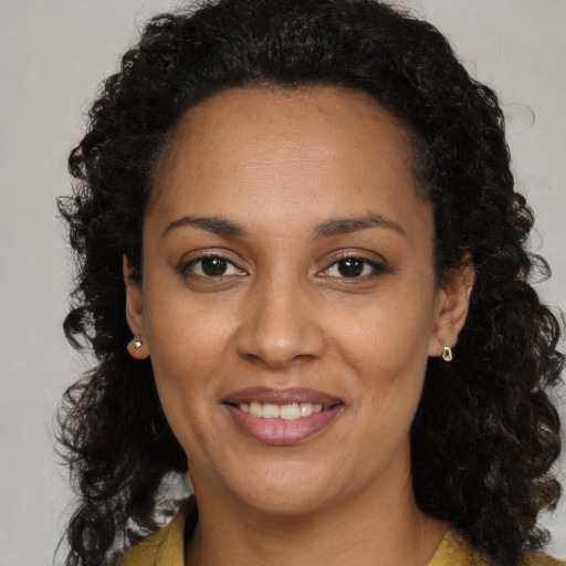 Joyful black young-adult female with long  brown hair and brown eyes