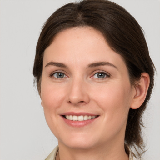 Joyful white young-adult female with medium  brown hair and grey eyes