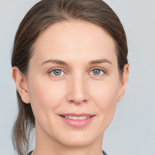 Joyful white young-adult female with medium  brown hair and grey eyes