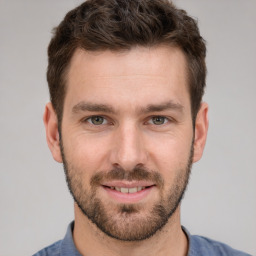 Joyful white young-adult male with short  brown hair and grey eyes