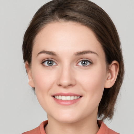 Joyful white young-adult female with medium  brown hair and grey eyes