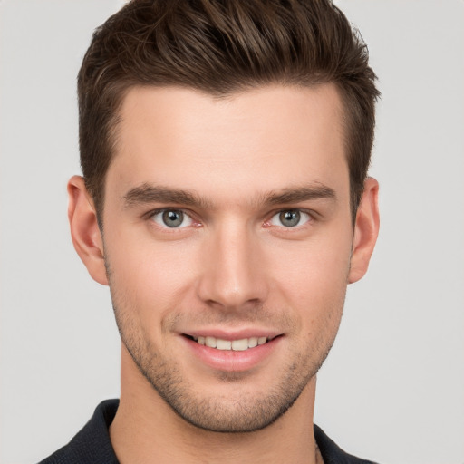 Joyful white young-adult male with short  brown hair and grey eyes