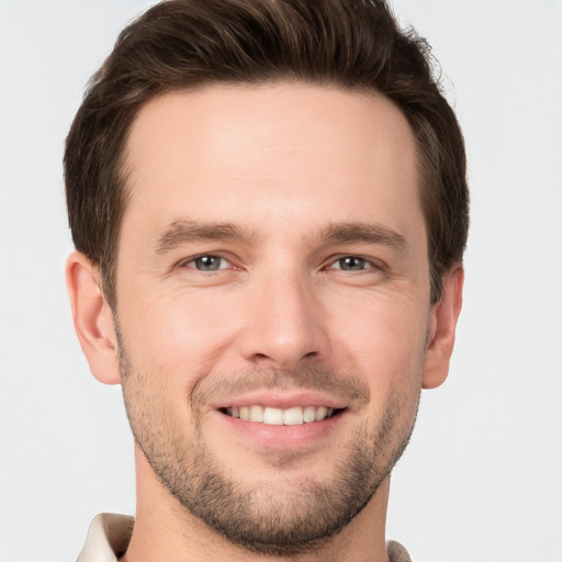 Joyful white young-adult male with short  brown hair and grey eyes