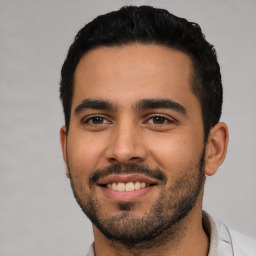 Joyful latino young-adult male with short  black hair and brown eyes