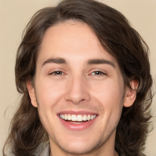 Joyful white young-adult male with long  brown hair and brown eyes