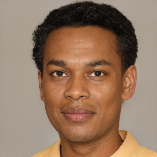 Joyful black young-adult male with short  black hair and brown eyes