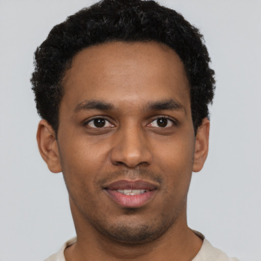 Joyful black young-adult male with short  black hair and brown eyes