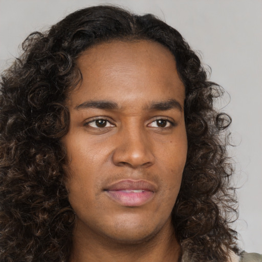 Joyful black young-adult male with long  brown hair and brown eyes