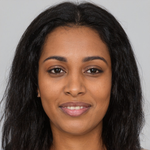 Joyful black young-adult female with long  black hair and brown eyes