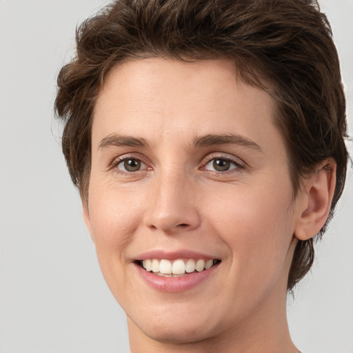 Joyful white young-adult female with short  brown hair and green eyes