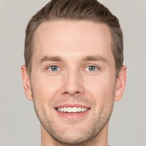 Joyful white young-adult male with short  brown hair and grey eyes