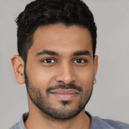 Joyful latino young-adult male with short  black hair and brown eyes