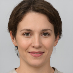 Joyful white young-adult female with medium  brown hair and grey eyes