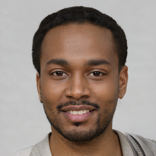 Joyful black young-adult male with short  black hair and brown eyes