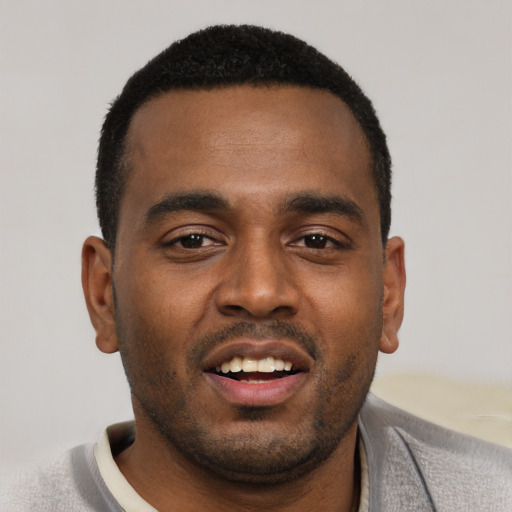 Joyful black young-adult male with short  black hair and brown eyes