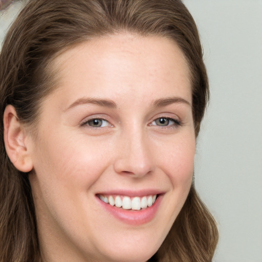 Joyful white young-adult female with long  brown hair and blue eyes