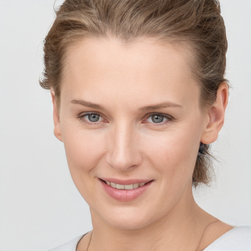 Joyful white young-adult female with medium  brown hair and grey eyes