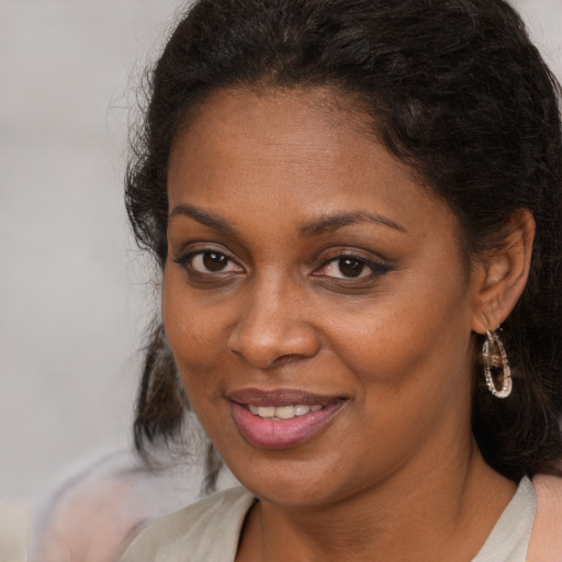 Joyful black young-adult female with long  brown hair and brown eyes
