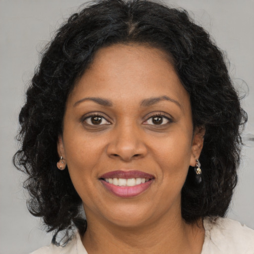 Joyful black young-adult female with long  brown hair and brown eyes